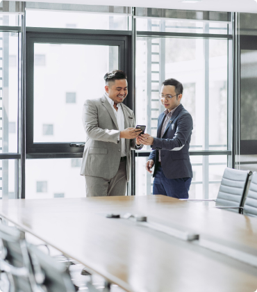 Two men looking at mobile phone in boardroom