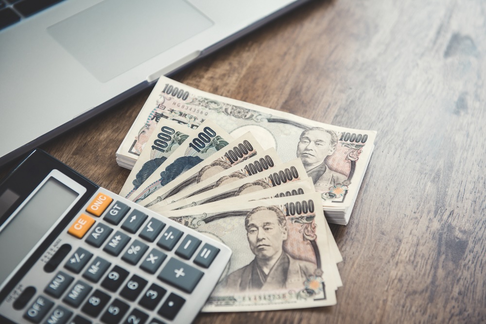 Money, Japanese yen banknotes, and calculator on wood table