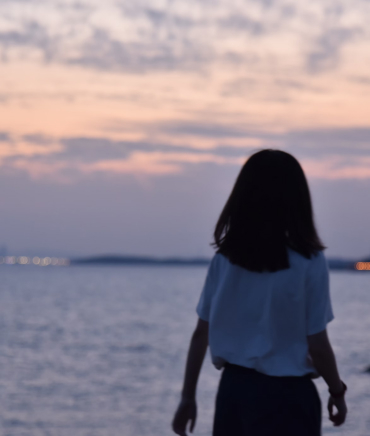 Woman walking away from camera at waters edge